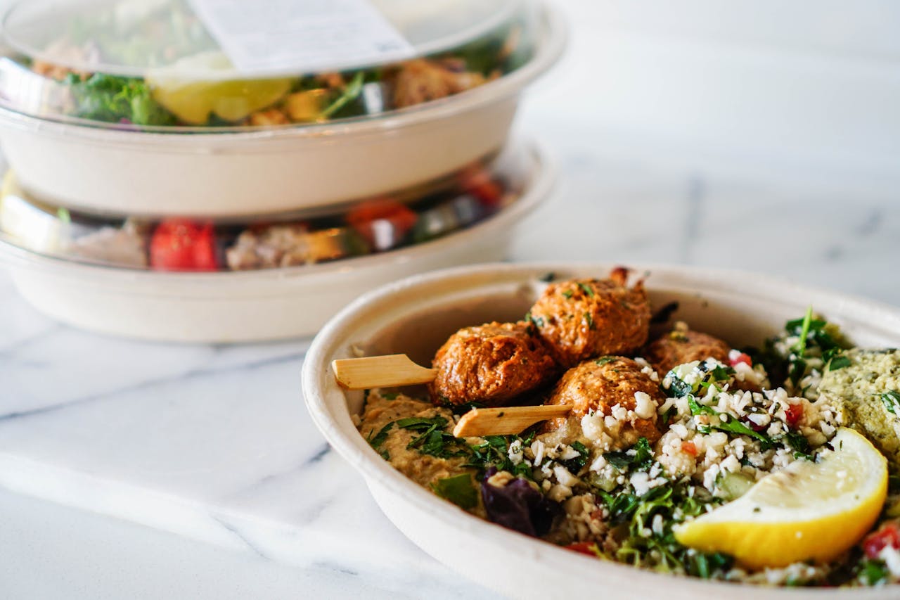 Delicious Mediterranean dish with falafel, hummus, and fresh salad in a takeaway bowl.